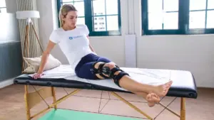 Frau mit Knie-Orthese auf einer Liege.