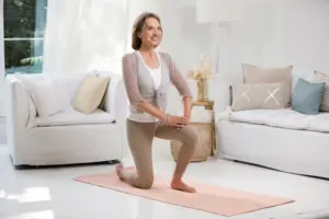 Frau macht eine Knieübung im Wohnzimmer als Teil ihres Heimtrainings.