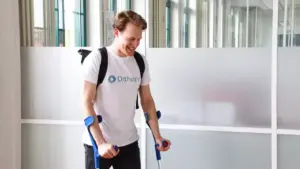 Mann geht mit Unterarmgehstützen und lächelt.