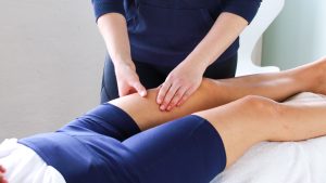 Therapeut macht manuelle Lymphdrainage am Bein des Patienten